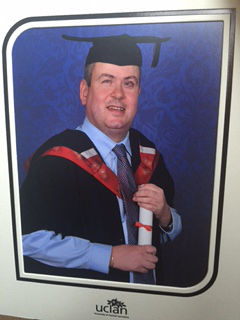 Image of Martin wearing Masters graduation cap and gown.